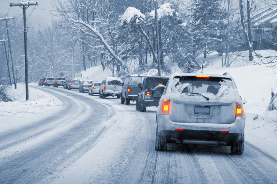 Cars drive slowly in snowy conditions demonstrating the need for safe wisconsin winter driving